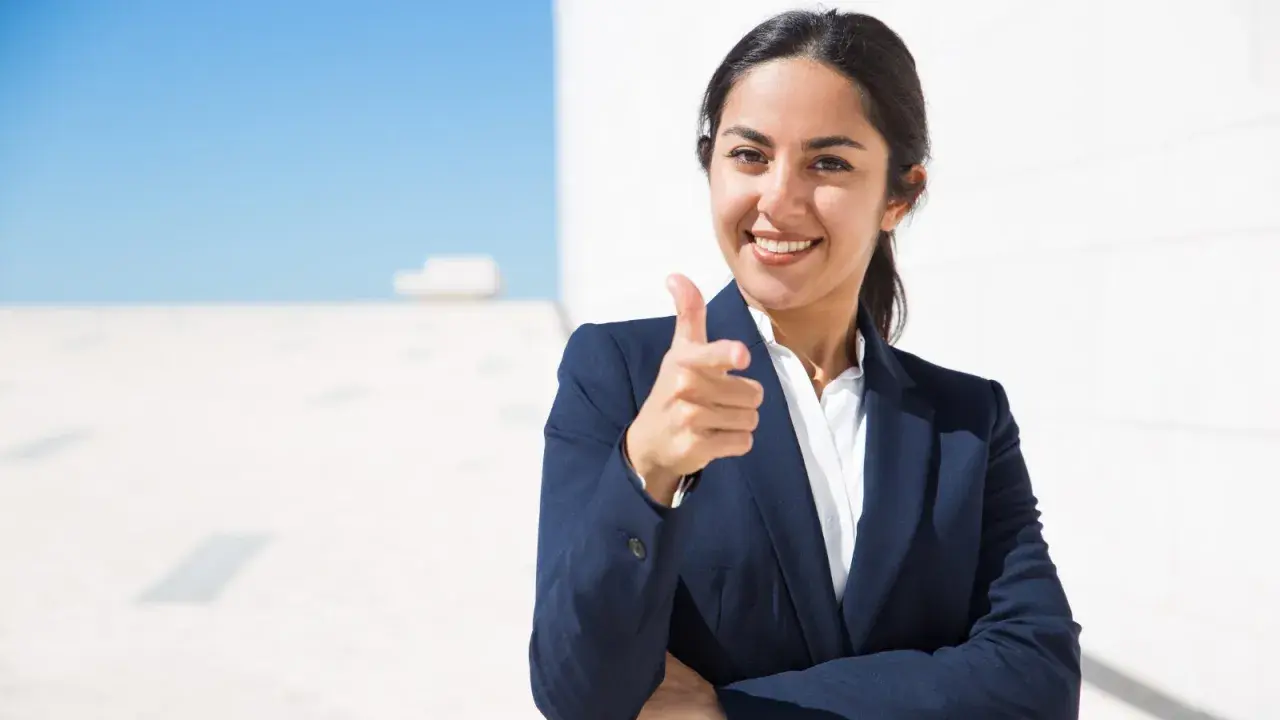 Donna in giacca blu indica con il dito, sorridendo. Un'immagine che simboleggia il ruolo di un hr business partner cosa fa: connette persone e obiettivi.