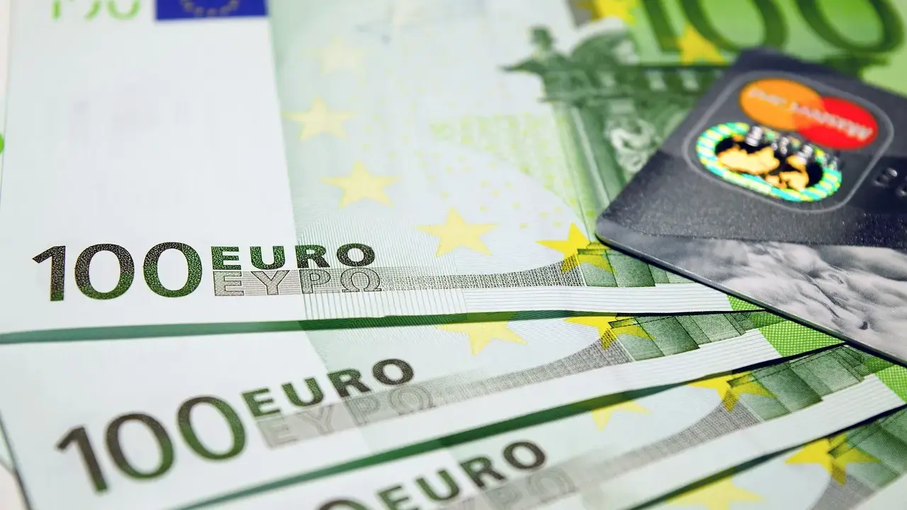 Banconote da 100 euro e una carta di credito, simboli dell'emissione busta paga e dell'accredito stipendio.