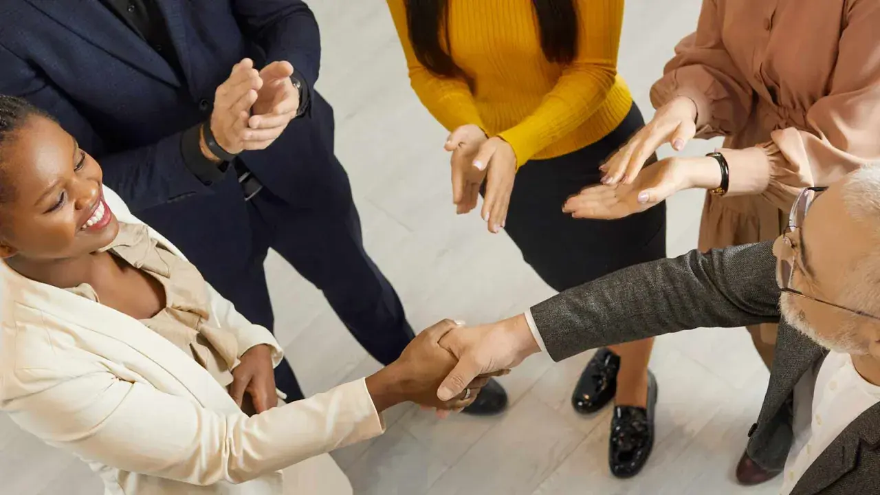 Un gruppo di persone applaude mentre due colleghi si stringono la mano. Un successo che fa ben sperare, anche se il premio produzione può essere tolto.