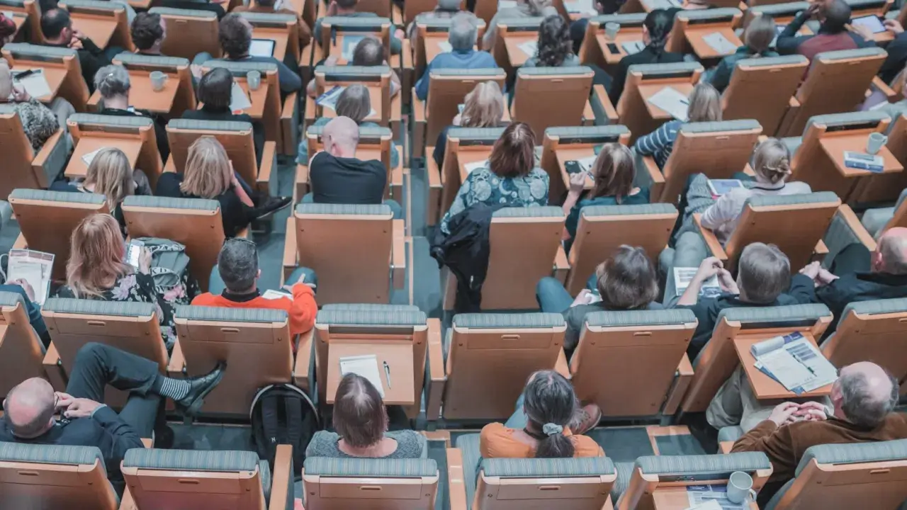 Un pubblico attento in un'aula, molti con quaderni e penne, pronti per nuovi concorsi non scaduti.