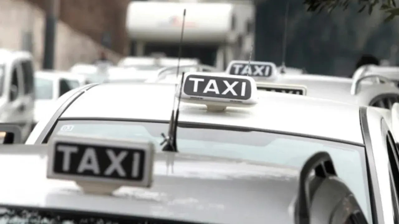 Code di taxi bianchi in attesa, un'immagine che fa riflettere su quanto guadagna un tassista.