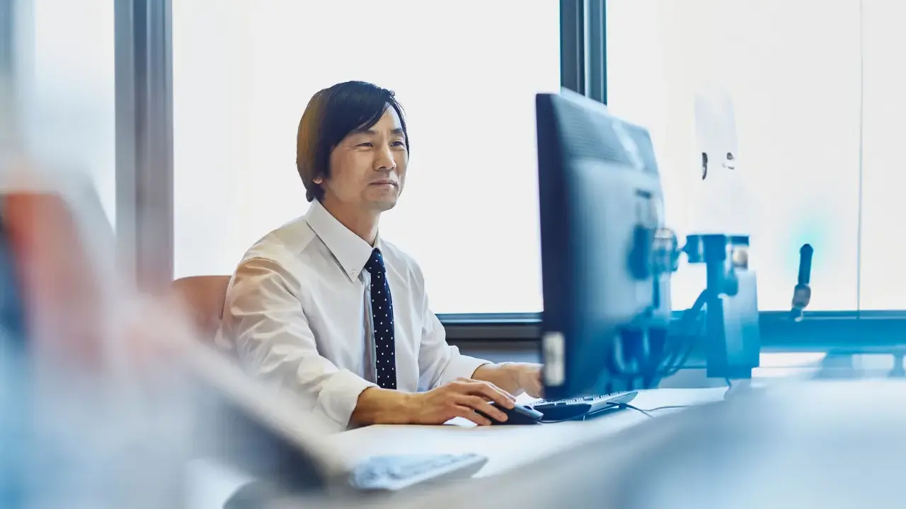 Uomo d'affari al computer, concentrato sul lavoro. Chissà quanto vengono pagati gli straordinari per questo impegno.