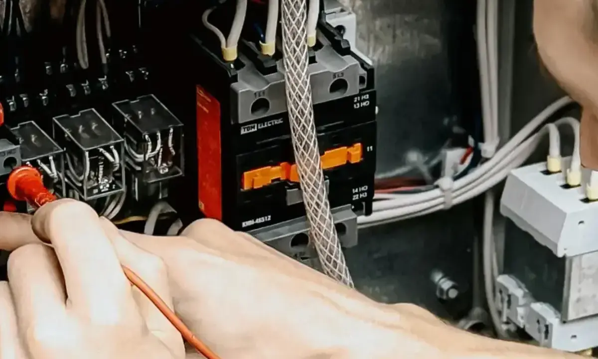 Mani che lavorano su un quadro elettrico, un passo fondamentale per capire come diventare elettricista.