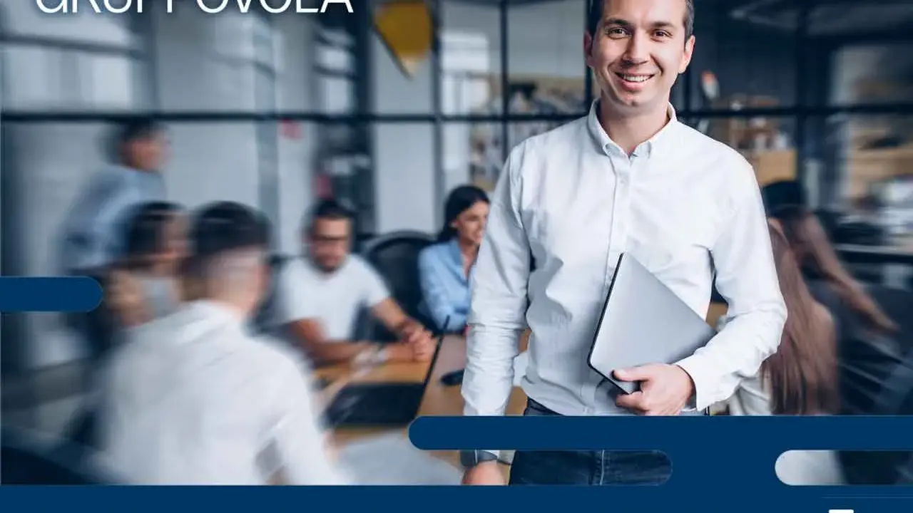Uomo sorridente con laptop, pronto per l'induction aziendale. Inserire una nuova risorsa in un team è un processo chiave.