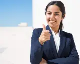 Donna in giacca blu indica con il dito, sorridendo. Un'immagine che simboleggia il ruolo di un hr business partner cosa fa: connette persone e obiettivi.