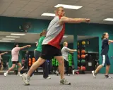 Uomini e donne in palestra eseguono movimenti coordinati, un esempio di lavoro di scienze motorie.