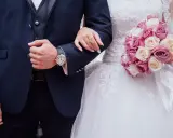 Coppia di sposi con bouquet di rose. Lui indossa un orologio, lei un anello. Inizia il loro congedo matrimoniale CCNL Commercio.