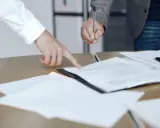 Un addetto ufficio del processo indica un documento mentre un collega firma.