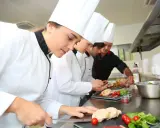 Giovani chef imparano da su chef chi è un maestro in cucina, preparando piatti raffinati.