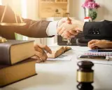 Avvocati si stringono la mano, simboli di giustizia e libri. La domanda "quanto guadagna un avvocato" è al centro di questo accordo.