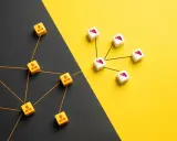 Dadi con icone di persone collegate da fili arancioni, che rappresentano l'outsourcing significato, su sfondo diviso nero e giallo.