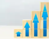 Blocchi di legno impilati a gradoni, con frecce blu che indicano crescita, simboleggiano il superamento dello skills gap e il progresso.