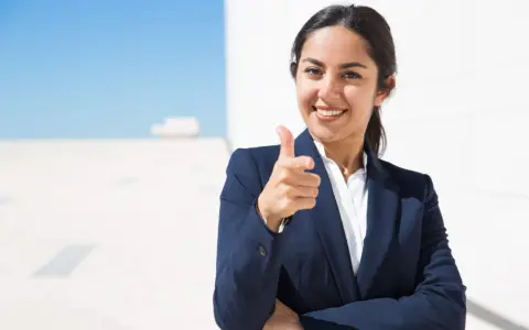 Donna in giacca blu indica con il dito, sorridendo. Un'immagine che simboleggia il ruolo di un hr business partner cosa fa: connette persone e obiettivi.