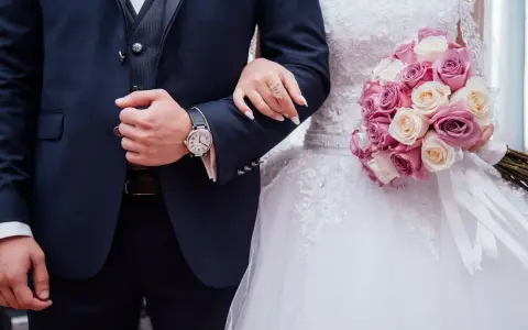 Coppia di sposi con bouquet di rose. Lui indossa un orologio, lei un anello. Inizia il loro congedo matrimoniale CCNL Commercio.