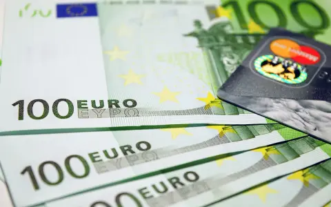 Banconote da 100 euro e una carta di credito, simboli dell'emissione busta paga e dell'accredito stipendio.