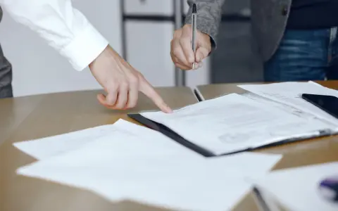 Un addetto ufficio del processo indica un documento mentre un collega firma.