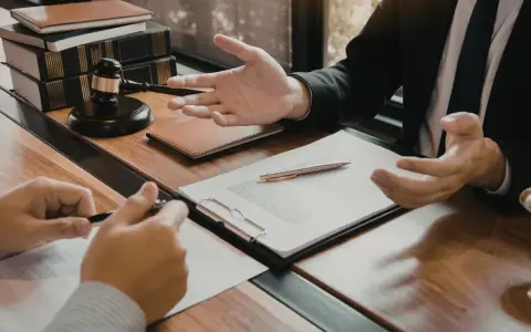 Consulenza legale: un avvocato, in veste di general counsel, spiega un contratto a un cliente, con martelletto e bilancia della giustizia sullo sfondo.