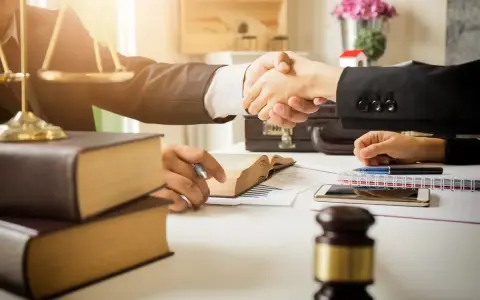 Avvocati si stringono la mano, simboli di giustizia e libri. La domanda "quanto guadagna un avvocato" è al centro di questo accordo.
