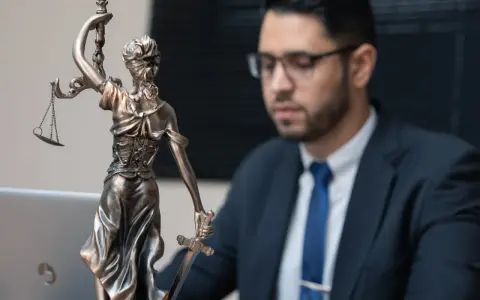 Statua della Giustizia e un uomo in giacca e cravatta, pronto per concorsi per laureati in giurisprudenza.