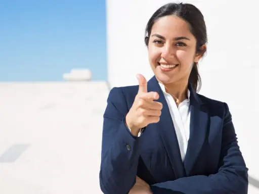 Donna in giacca blu indica con il dito, sorridendo. Un'immagine che simboleggia il ruolo di un hr business partner cosa fa: connette persone e obiettivi.