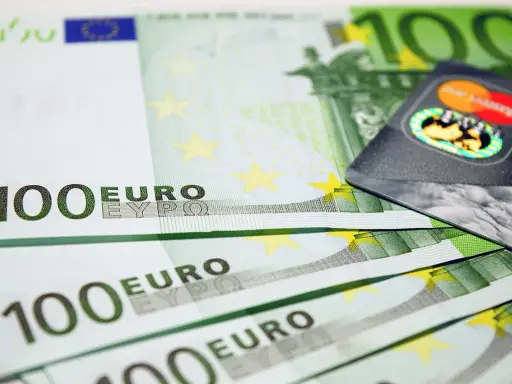 Banconote da 100 euro e una carta di credito, simboli dell'emissione busta paga e dell'accredito stipendio.