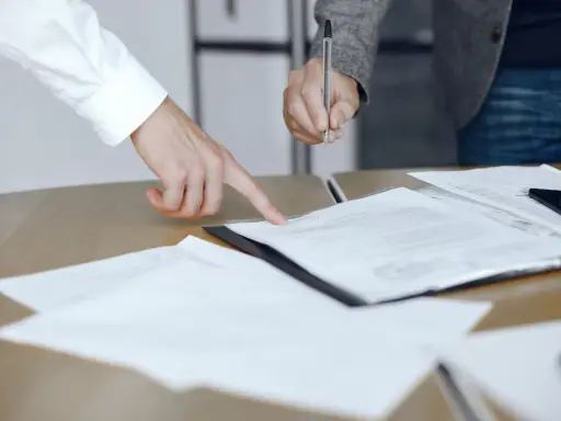 Un addetto ufficio del processo indica un documento mentre un collega firma.
