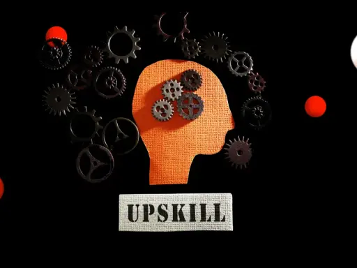 Ingranaggi dentro una testa stilizzata, circondati da altri ingranaggi e sfere rosse. Il concetto di upskilling significato è rappresentato dal movimento e dall'apprendimento continuo.