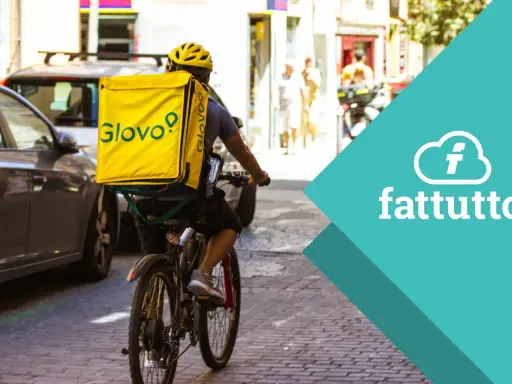 Corriere in bici con zaino giallo Glovo, pronto a consegnare. Scopri come lavorare con Glovo e unisciti alla squadra!