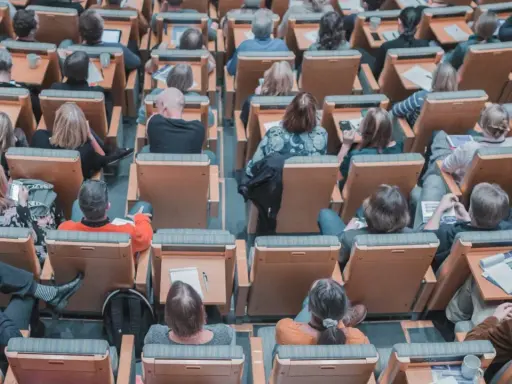 Un pubblico attento in un'aula, molti con quaderni e penne, pronti per nuovi concorsi non scaduti.