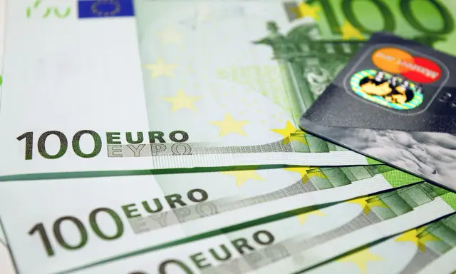 Banconote da 100 euro e una carta di credito, simboli dell'emissione busta paga e dell'accredito stipendio.