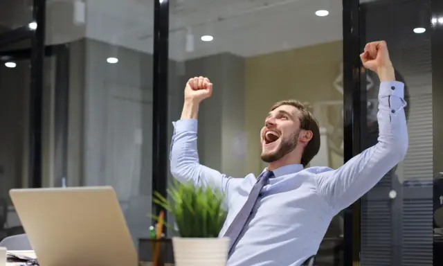 Uomo esulta in ufficio, festeggiando un successo legato alla mobilità pubblica amministrazione.