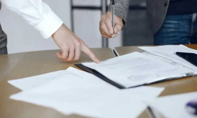 Un addetto ufficio del processo indica un documento mentre un collega firma.