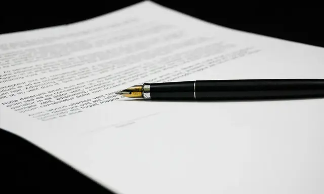 Una penna stilografica nera su un foglio di testo, forse una lettera di richiamo per assenza ingiustificata.