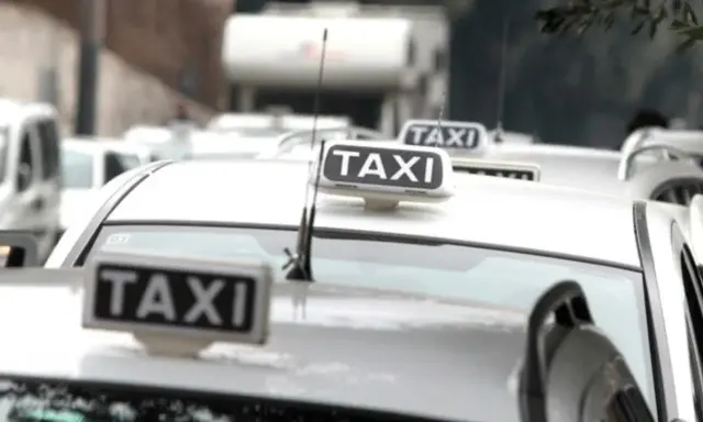 Code di taxi bianchi in attesa, un'immagine che fa riflettere su quanto guadagna un tassista.