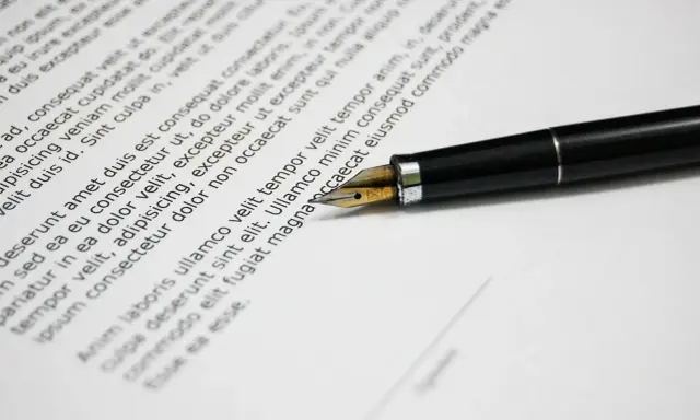 Una penna stilografica su un documento, che ricorda una esempio domanda di trasferimento motivata.