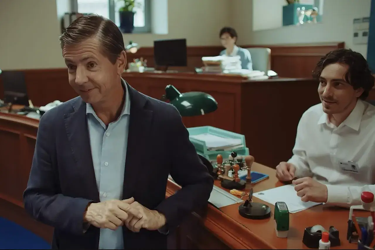 Un uomo in giacca e camicia parla con un collega. L'account manager cosa fa? Gestisce relazioni e documenti in ufficio.